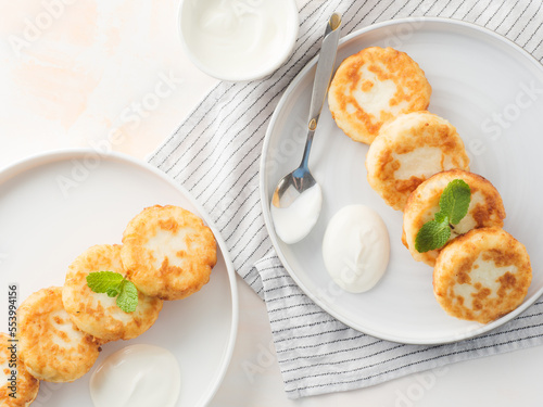 Cottage cheese pancakes, syrniki, on a light background. Copy space.