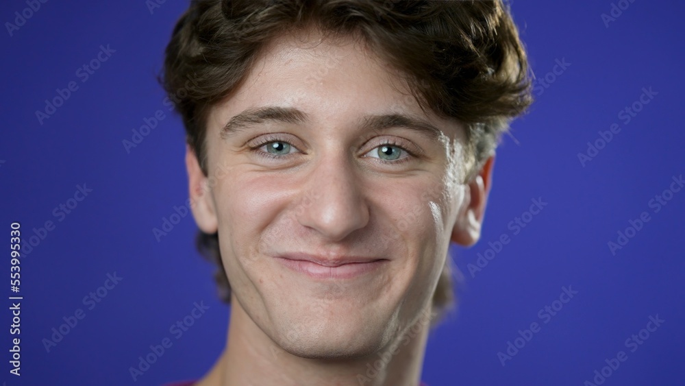 Fototapeta premium Closeup portrait of smiling happy young hipster man 20s isolated on solid purple background in studio