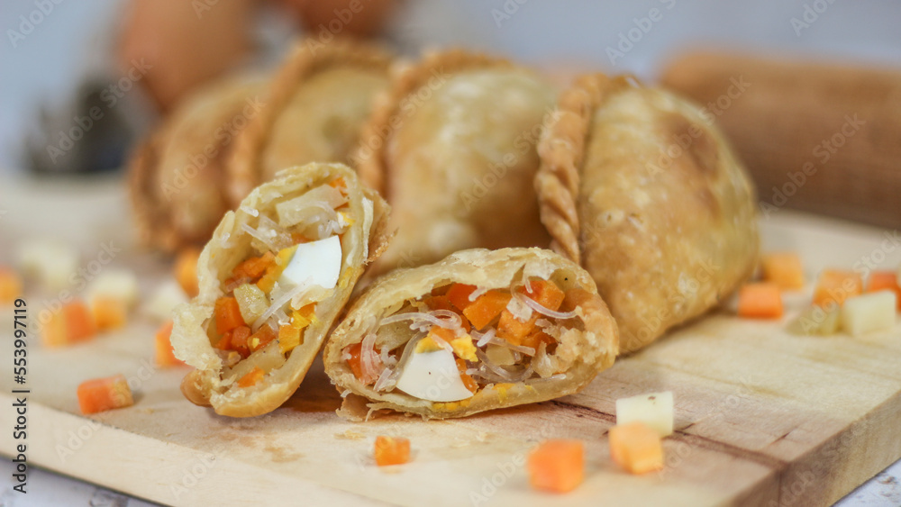 a close up of pastel cake which is a traditional indonesian food. filled with chicken, vegetables, or boiled eggs and served with sauce or chili. Indonesian traditional food photo concept.