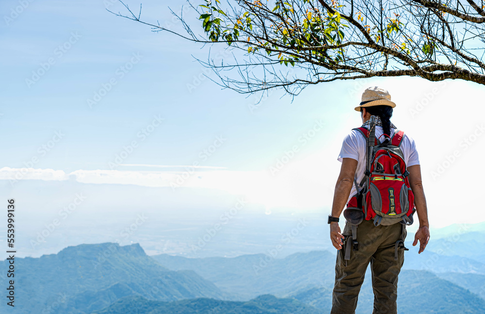 The back of a male tourist Standing looking at the beautiful view on the high mountain. to people travel and backpacker concept.
