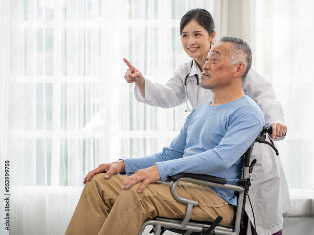 Senior man patient is in wheelchair and young female nurse taking care of him in nursing home. Asian doctor woman supports old man patient to recovery at hospital. Aged people at rehabilitation.