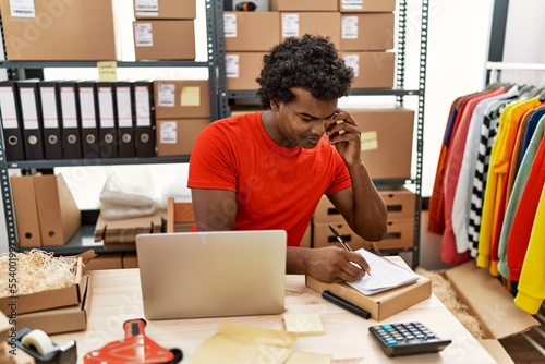 Young south east man talking on the smartphone writing order on notebook at storehouse © Krakenimages.com