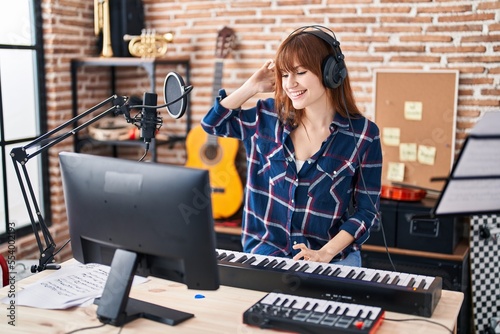 Young woman musician playing piano keyboard at music studio