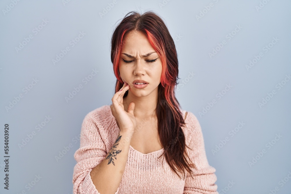 Young caucasian woman wearing pink sweater over isolated background touching mouth with hand with painful expression because of toothache or dental illness on teeth. dentist concept. Young caucasian woman wearing pink sweater over isolated background touching mouth with hand with painful expression because of toothache or dental illness on teeth. dentist concept.