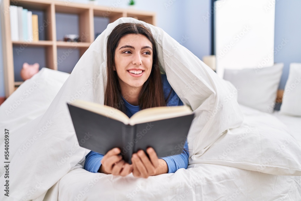 Young beautiful hispanic woman reading book lying on bed at bedroom Young beautiful hispanic woman reading book lying on bed at bedroom
