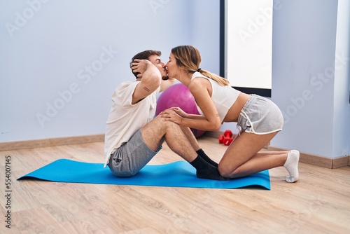 Young man and woman couple doing abs exercise kissing at sport center