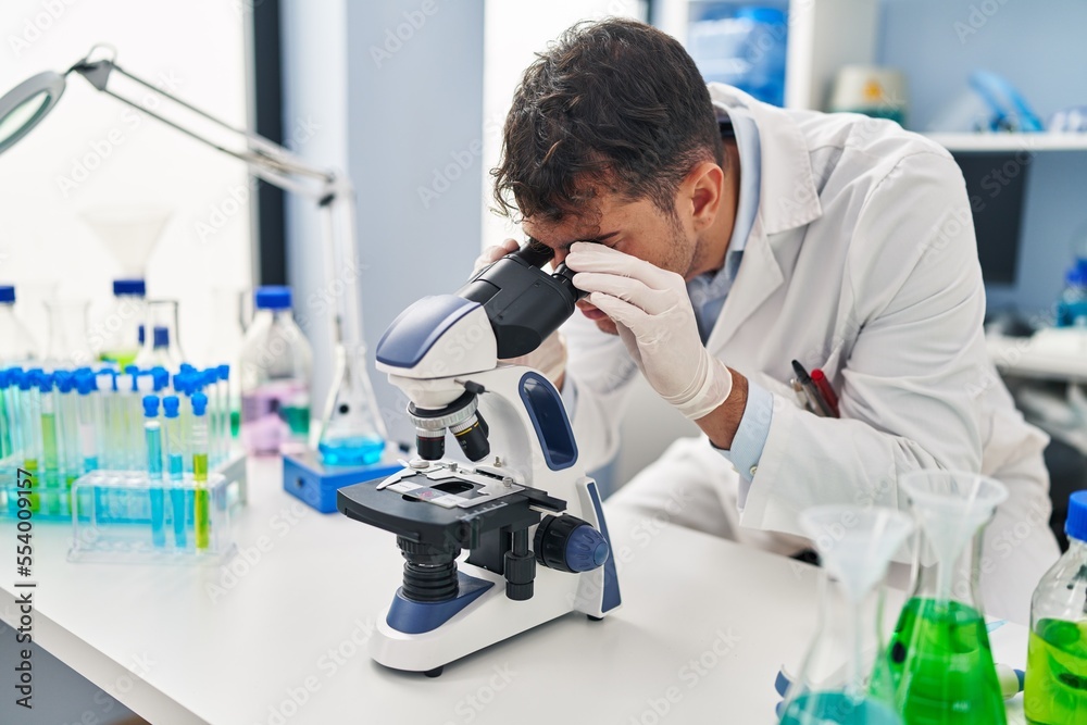 Young hispanic man scientist using microscope at laboratory Young hispanic man scientist using microscope at laboratory