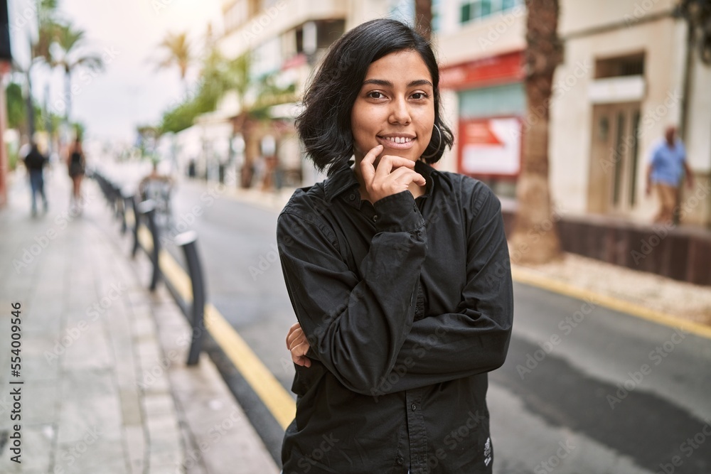 Young latin woman smiling confident standing with arms crossed gesture at street