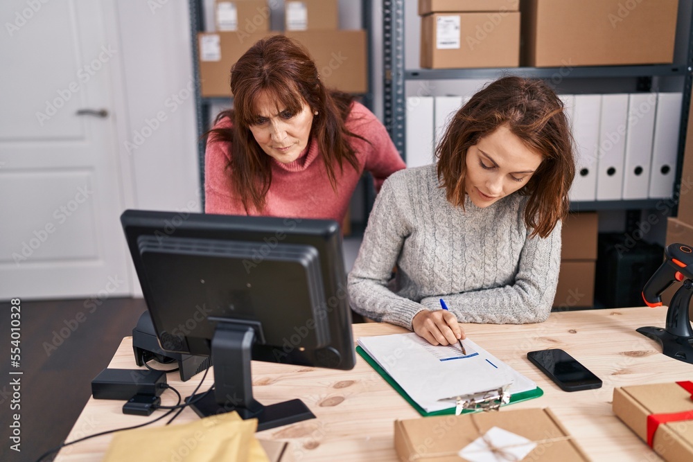 Two women ecommerce business workers writing on document at office Two women ecommerce business workers writing on document at office