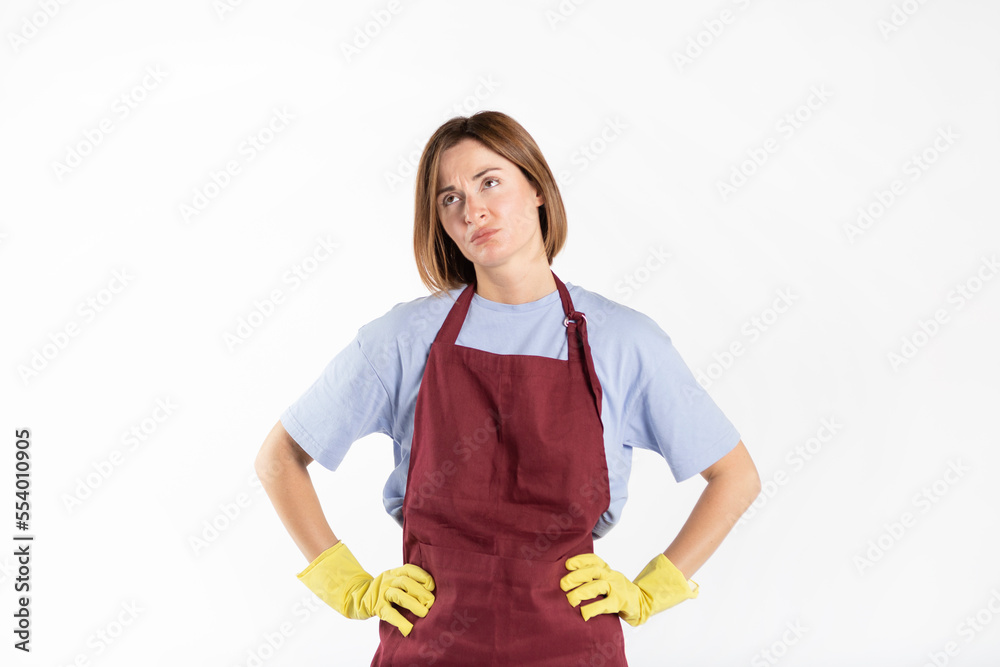 Sad and tired woman wearing apron and rubber gloves standing isolated on white background Sad and tired woman wearing apron and rubber gloves standing isolated on white background