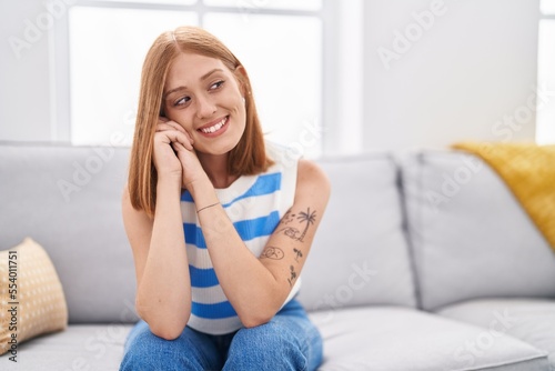 Young redhead woman smiling confident sitting on sofa at home