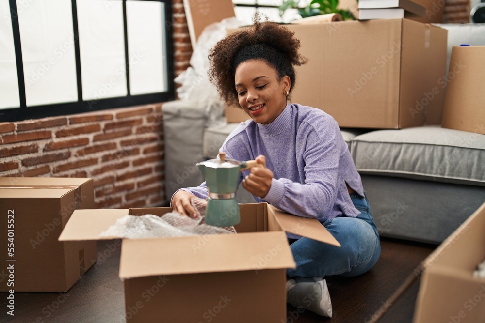 Young african american woman smiling confident unpacking coffee maker at new home Young african american woman smiling confident unpacking coffee maker at new home