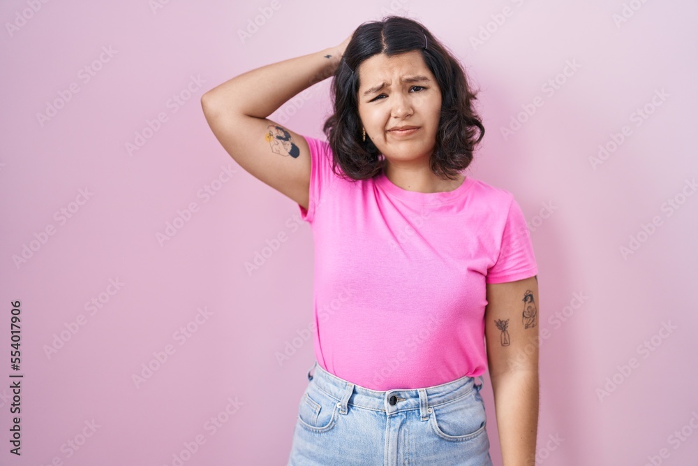 Young hispanic woman standing over pink background confuse and wondering about question. uncertain with doubt, thinking with hand on head. pensive concept. Young hispanic woman standing over pink background confuse and wondering about question. uncertain with doubt, thinking with hand on head. pensive concept.