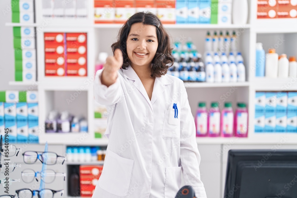 Young woman pharmacist smiling confident shake hand at pharmacy