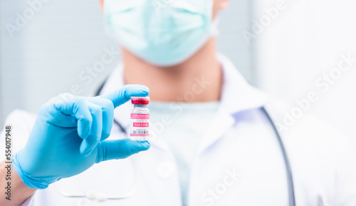 Young doctor or scientist in uniform wearing a face mask showing up coronavirus vaccine, nurse man holding bottle COVID-19 vaccination at laboratory, Healthcare And Medical concept