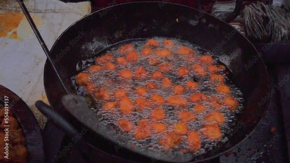 Lentil fritters or Indian Pakora being deep fried in street side food stall of India. Top view, Natural evening light. Lentil fritters or Indian Pakora being deep fried in street side food stall of India. Top view, Natural evening light.