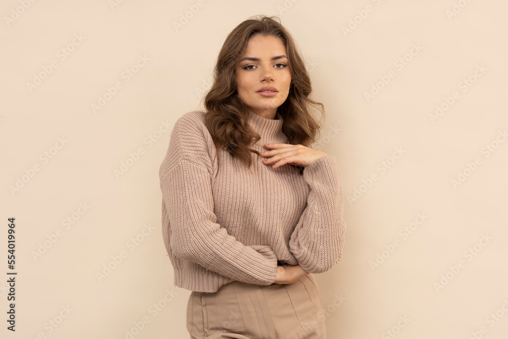 Studio shot of attractive young woman in brown sweater on brown background. Studio shot of attractive young woman in brown sweater on brown background.