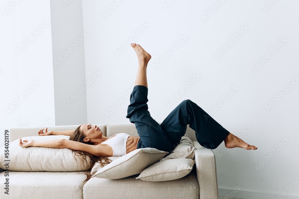 Woman having fun and lying on the couch with her legs up happily resting from work
