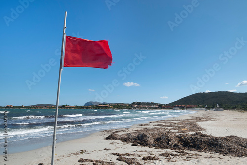 Fototapeta Naklejka Na Ścianę i Meble -  Red flag at beautiful white sandy beach at San Teodoro Sardinia.