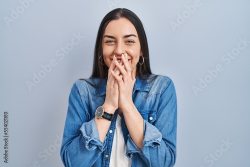 Schilderij op canvas Hispanic woman standing over blue background laughing and embarrassed giggle cov
