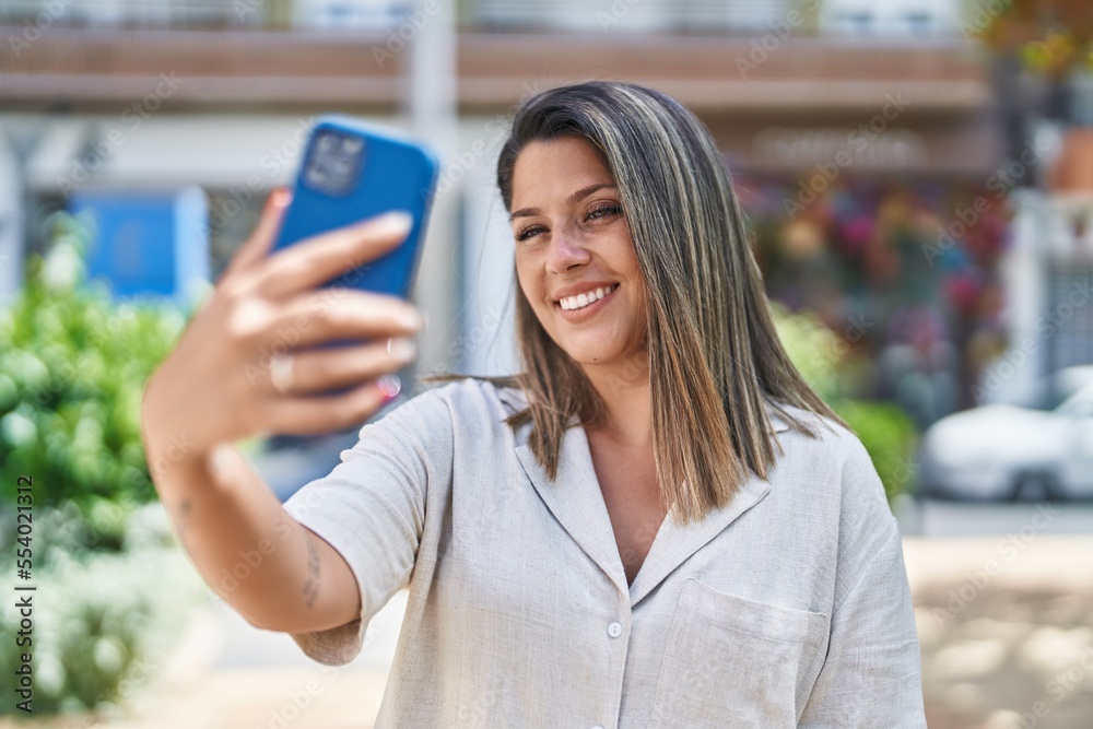 Young hispanic woman smiling confident making selfie by the smartphone at street