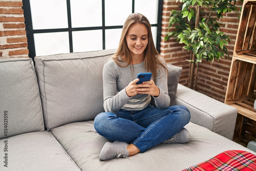 Young blonde woman smiling confident using smartphone at home
