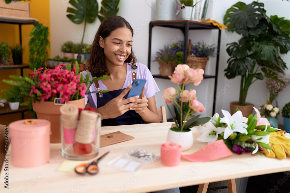 Young african american woman florist smiling confident using smartphone at flower shop