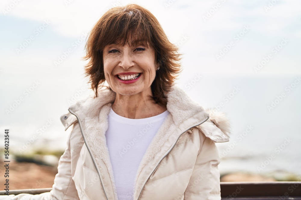 Middle age woman smiling confident standing at seaside Middle age woman smiling confident standing at seaside