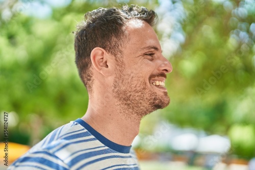 Young hispanic man smiling confident looking to the side at park