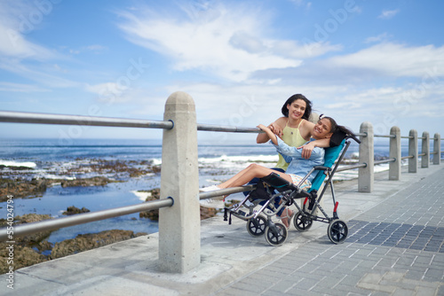 Portrait happy mother and disabled daughter in pushchair at beach photo