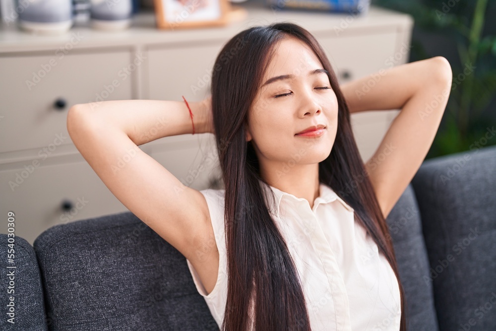 Young chinese woman relaxed with hands on head sitting on sofa at home Young chinese woman relaxed with hands on head sitting on sofa at home