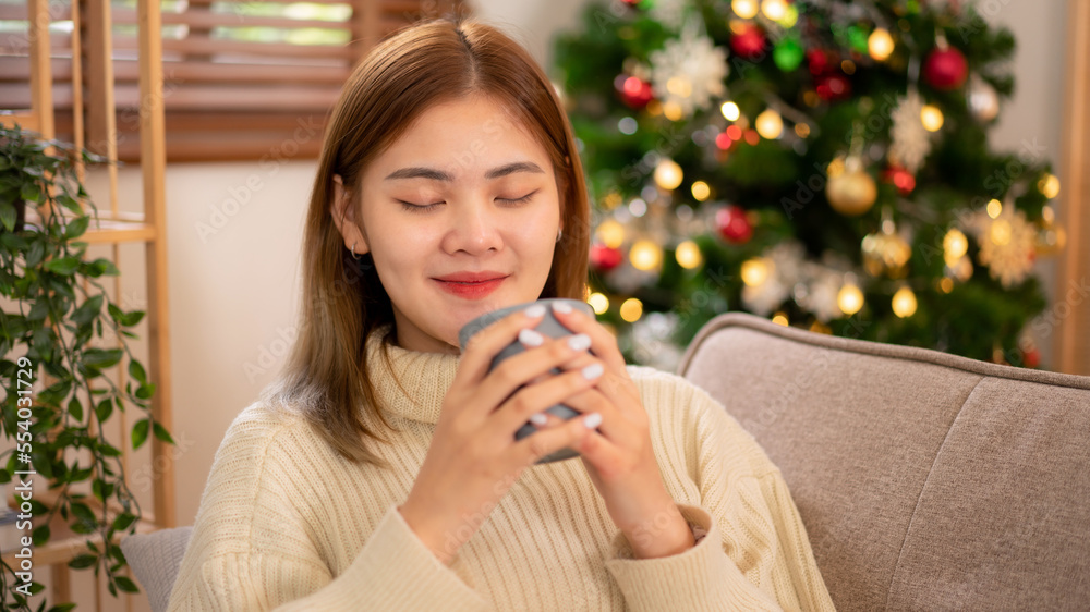Young asian woman drinking coffee and reading a book while wearing sweater and sitting to relaxation Young asian woman drinking coffee and reading a book while wearing sweater and sitting to relaxation