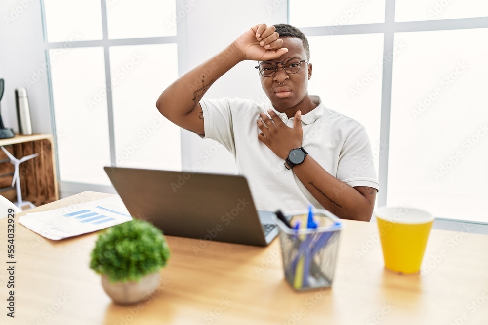 Young african man working at the office using computer laptop touching forehead for illness and fever, flu and cold, virus sick Young african man working at the office using computer laptop touching forehead for illness and fever, flu and cold, virus sick