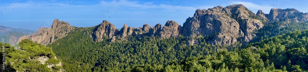 Very rocky Corsican mountain range of the Aiguilles de Bavella in summer, very tall and wide massif of France, near Zonza in Conca forest, with some trees in bottom Very rocky Corsican mountain range of the Aiguilles de Bavella in summer, very tall and wide massif of France, near Zonza in Conca forest, with some trees in bottom
