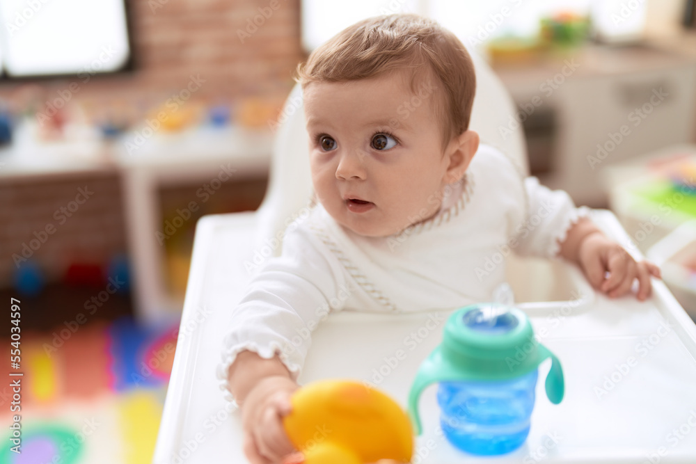 Adorable toddler sitting on baby highchair at kindergarten Adorable toddler sitting on baby highchair at kindergarten