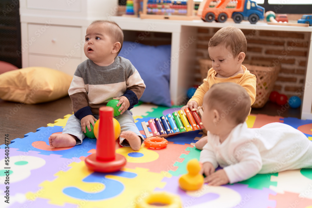 Group of toddlers playing with toys sitting on floor at kindergarten Group of toddlers playing with toys sitting on floor at kindergarten