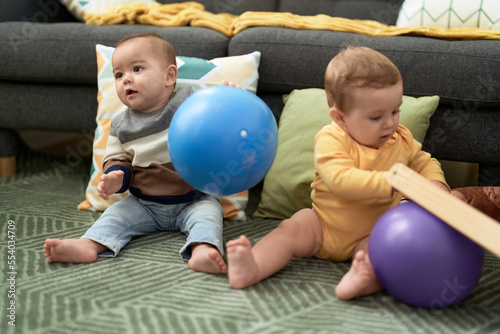Two toddlers playing with balls sitting on floor at home © Krakenimages.com