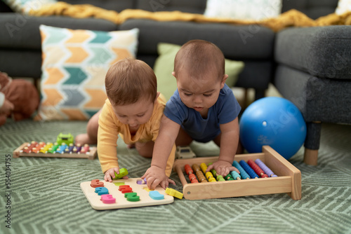 Two toddlers playing with maths toys sitting on floor at home