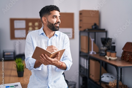 Young arab man business worker writing on notebook standing at office