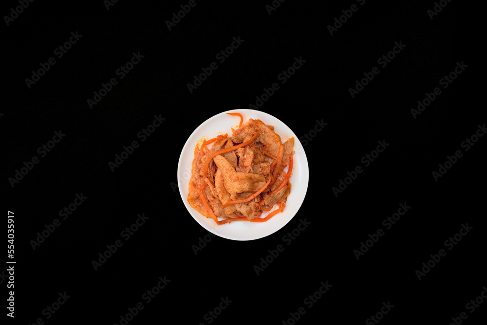 Fototapeta premium Delicious asian soy vegan meat salad on white plate on black background. Selective focus. Asian food concept