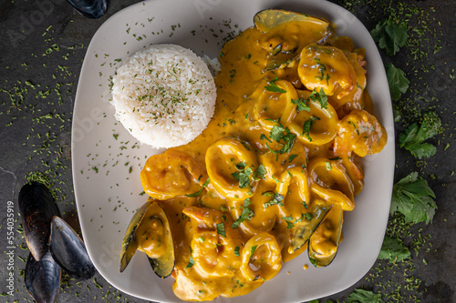 Pescado a la Macho is a Peruvian seafood dish with a cream based seafood sauce containing Peruvian spices and pieces of clams, mussels and calamari rings with rice. photo