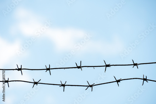Barbed wire against the sky. A security fence on the territory of a prison or airport. Ways to protect your property.