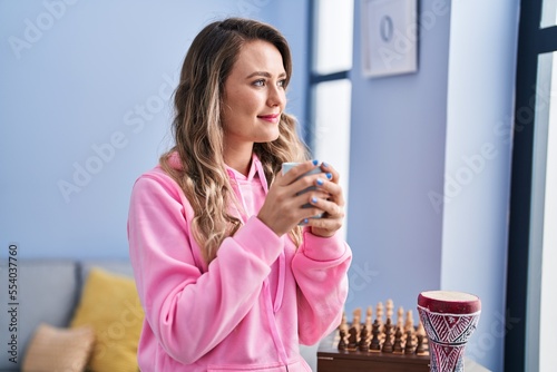 Young woman drinking coffee standing at home
