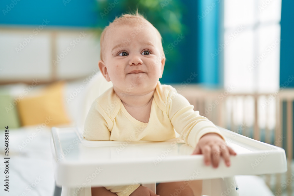 Adorable caucasian baby sitting on highchair at bedroom