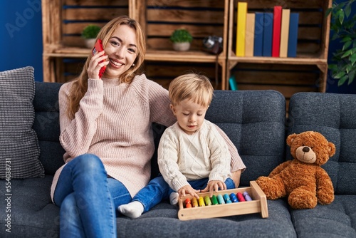 Mother and son talking on the smartphone and playing with abacus at home