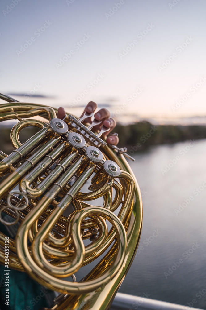 Man blowing his horn on a bridge with the river in front of him