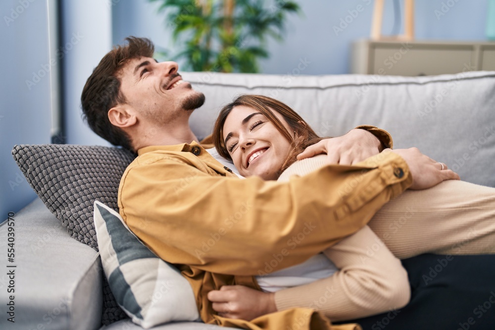 Mand and woman couple hugging each other lying on sofa at home