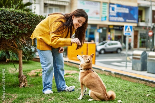 Beautiful young woman training shiba inu dog at park