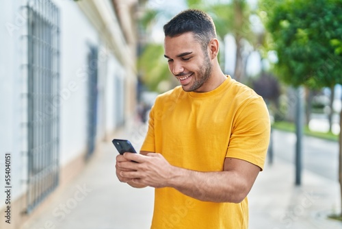 Young hispanic man smiling confident using smartphone at street © Krakenimages.com