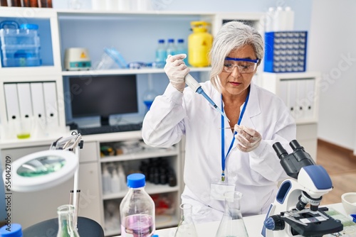 Middle age woman wearing scientist uniform working at laboratory